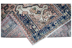 A handwoven vintage Persian rug featuring a floral pattern in blue, pink, and cream tones.