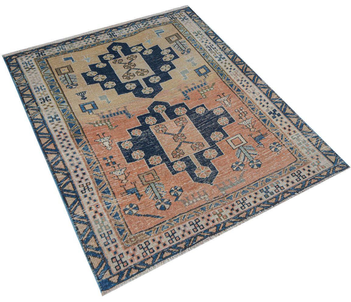 A handwoven vintage Persian rug featuring geometric blue medallions on a peach and tan field.