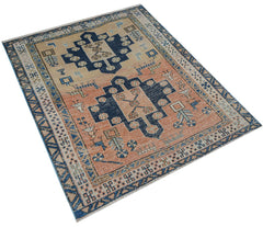 A handwoven vintage Persian rug featuring geometric blue medallions on a peach and tan field.