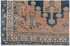 A handwoven vintage Persian rug featuring geometric patterns in shades of blue and peach.