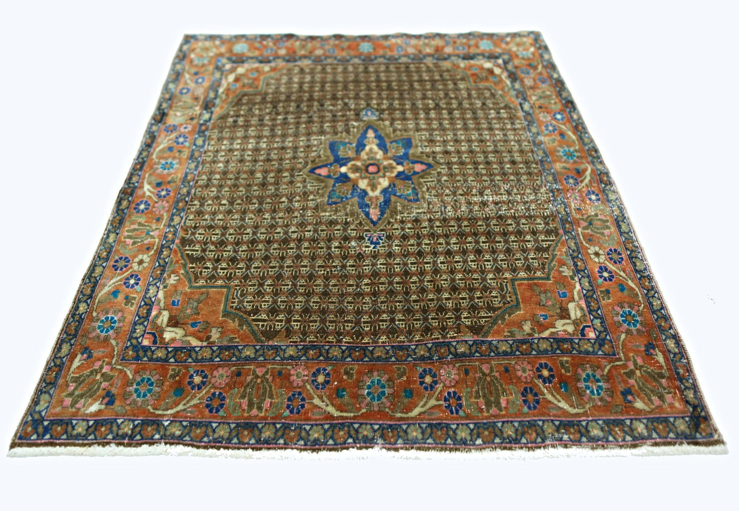 A vintage handmade Persian rug featuring a brown field with a central blue floral medallion.