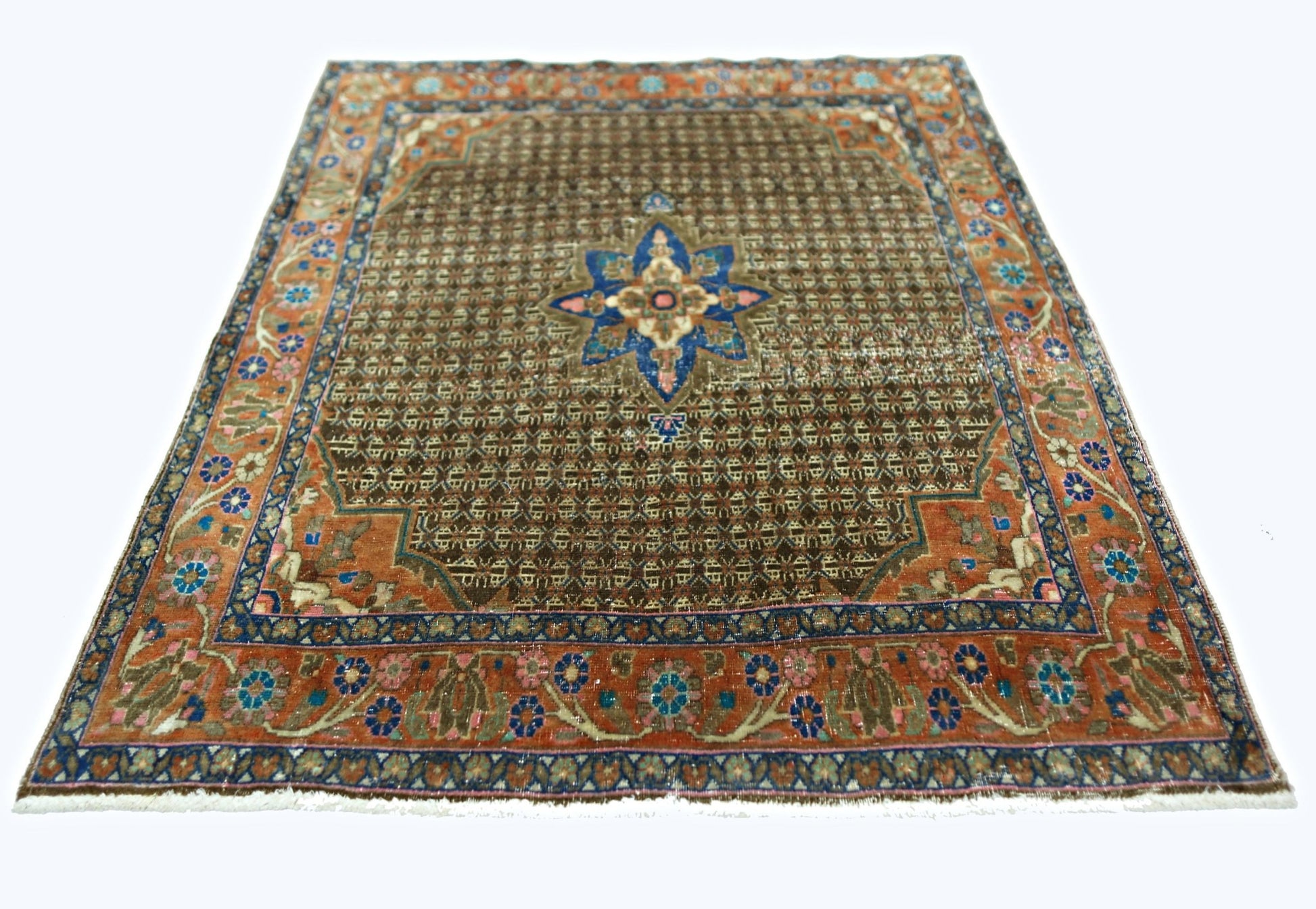 A vintage handmade Persian rug featuring a brown field with a central blue floral medallion.