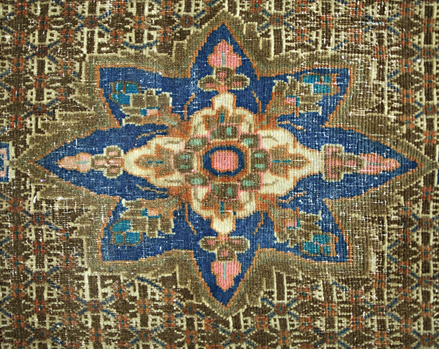 A vintage Persian rug featuring a central blue star medallion with intricate floral patterns.