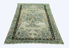 A vintage handmade Persian rug featuring a faded floral pattern in blue and brown tones.