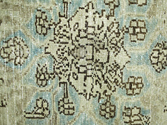A close-up of a vintage Persian rug featuring a geometric floral pattern in blue and beige.