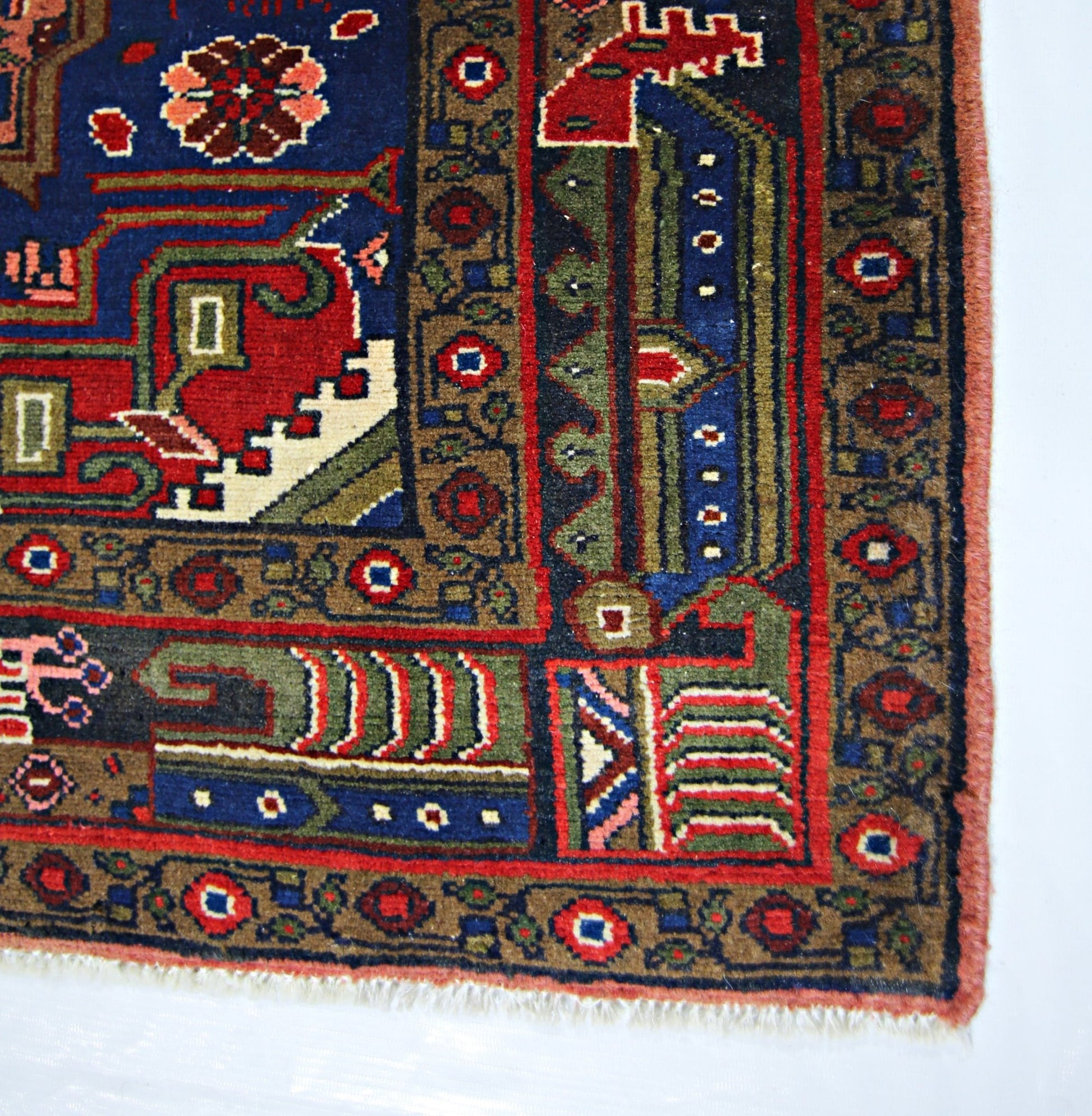 A vintage handmade Persian rug featuring intricate geometric patterns in blue, red, and green.