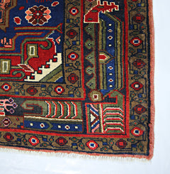 A vintage handmade Persian rug featuring intricate geometric patterns in blue, red, and green.
