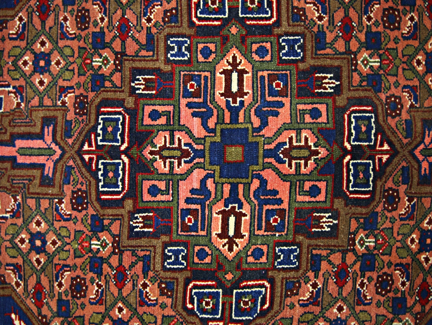A vintage Persian rug featuring a geometric central medallion in shades of blue, red, and green.
