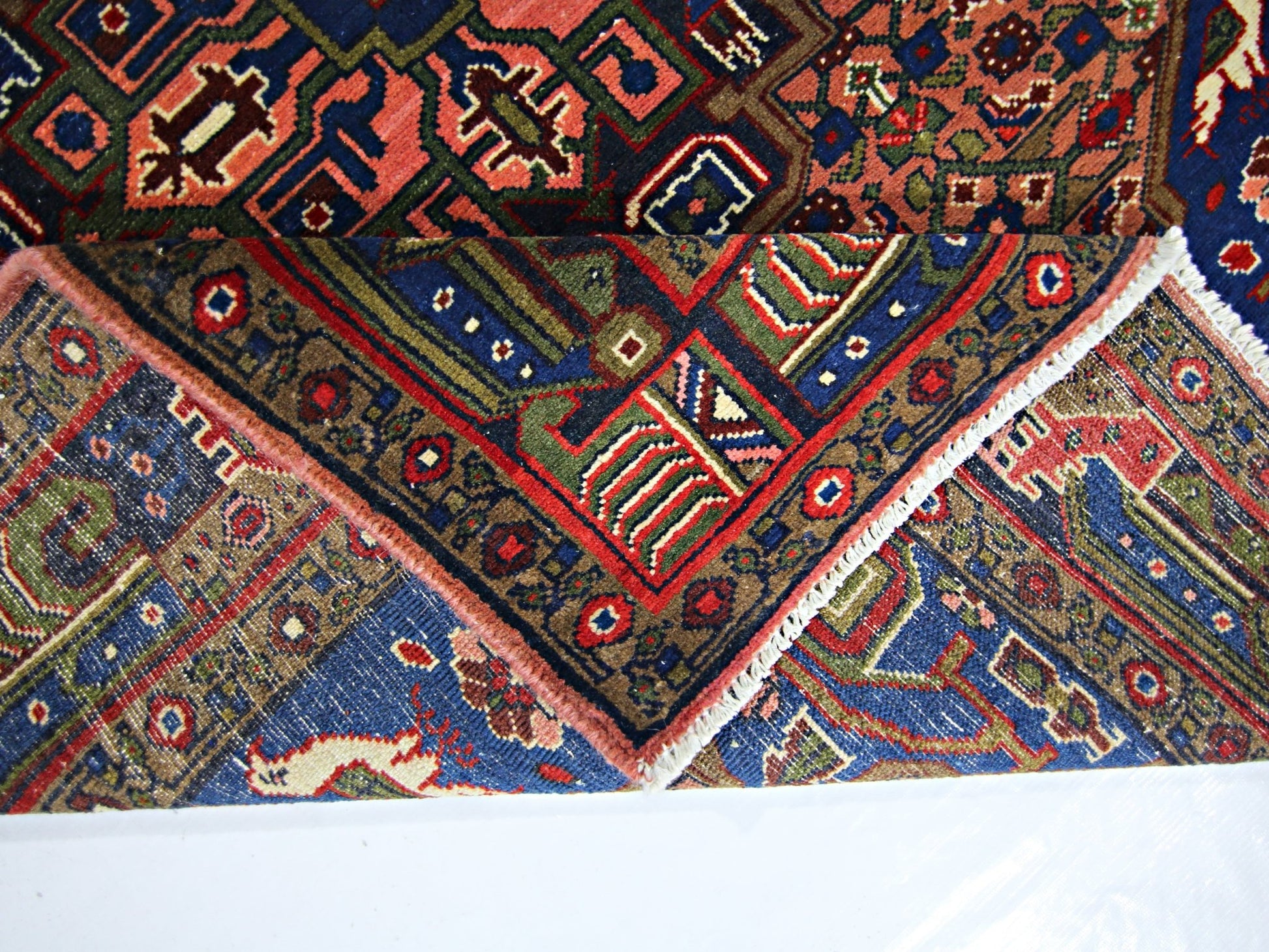 A vintage handmade Persian rug featuring intricate geometric patterns in red, blue, and green.