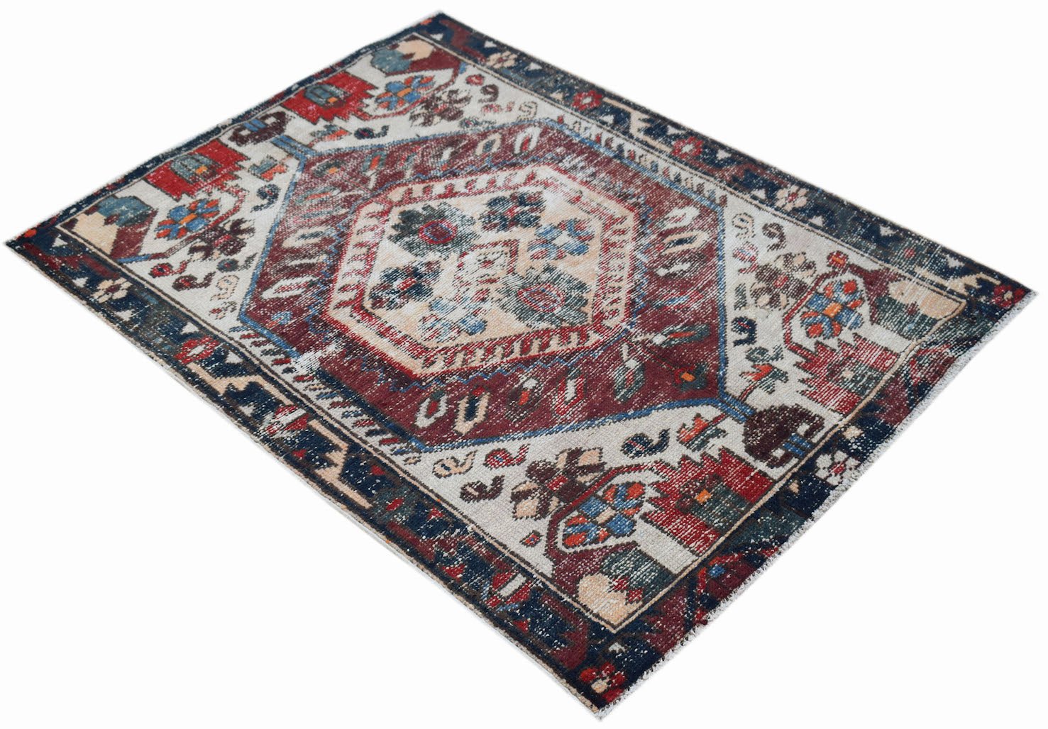 A vintage handwoven Persian rug featuring a central medallion in red, blue, and cream tones.