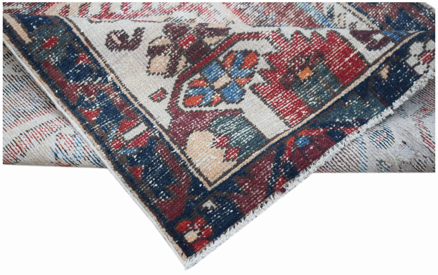A handwoven vintage Persian rug featuring a geometric floral pattern in red, blue, and cream.