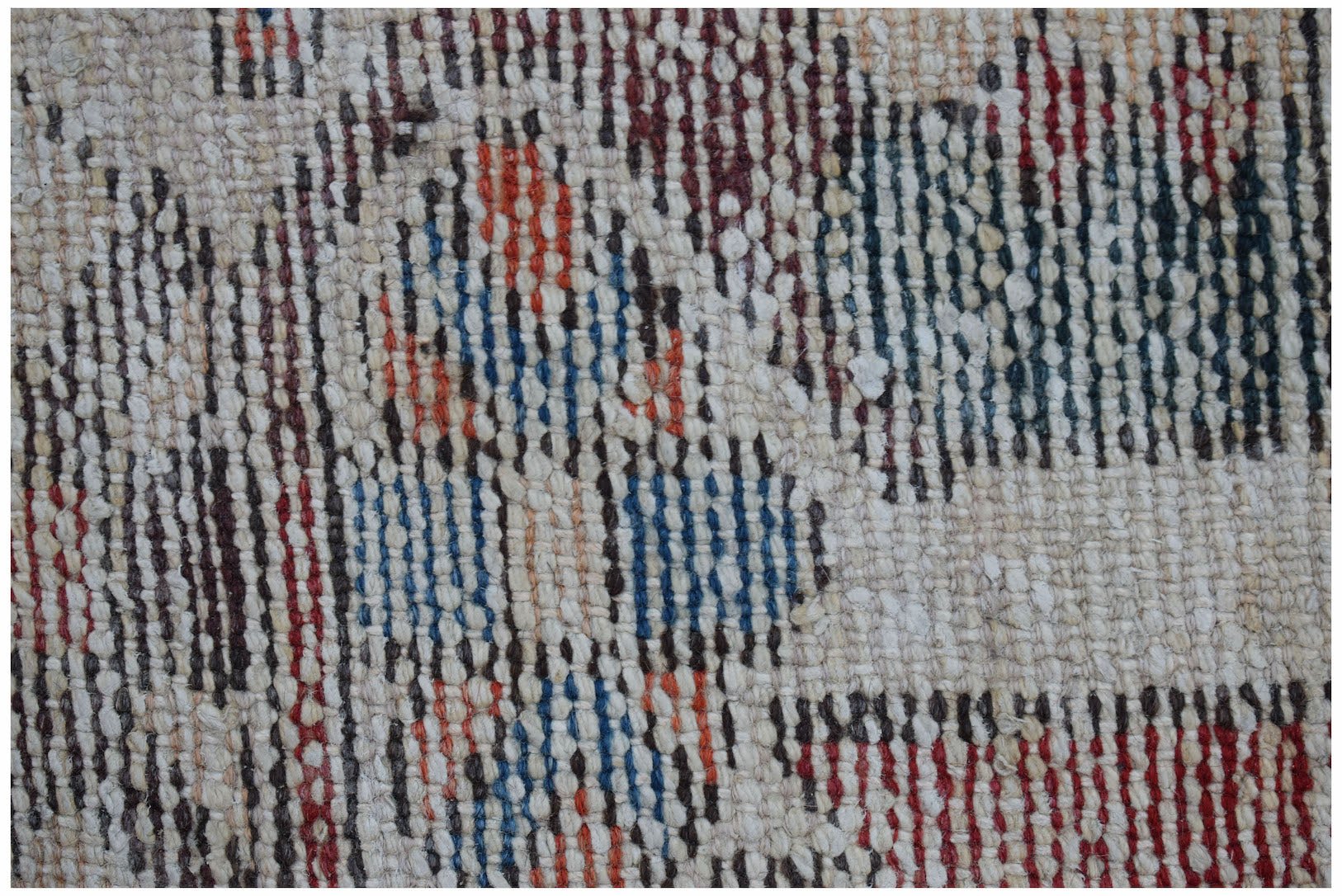 Close-up of a vintage handwoven Persian rug with a textured weave and geometric patterns in red, blue, and brown.