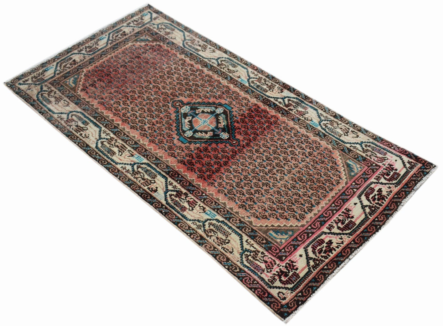 A handwoven vintage Persian rug featuring a central medallion on a faded red field.
