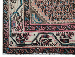 A handwoven vintage Persian rug featuring a pink central field with paisley patterns and borders.