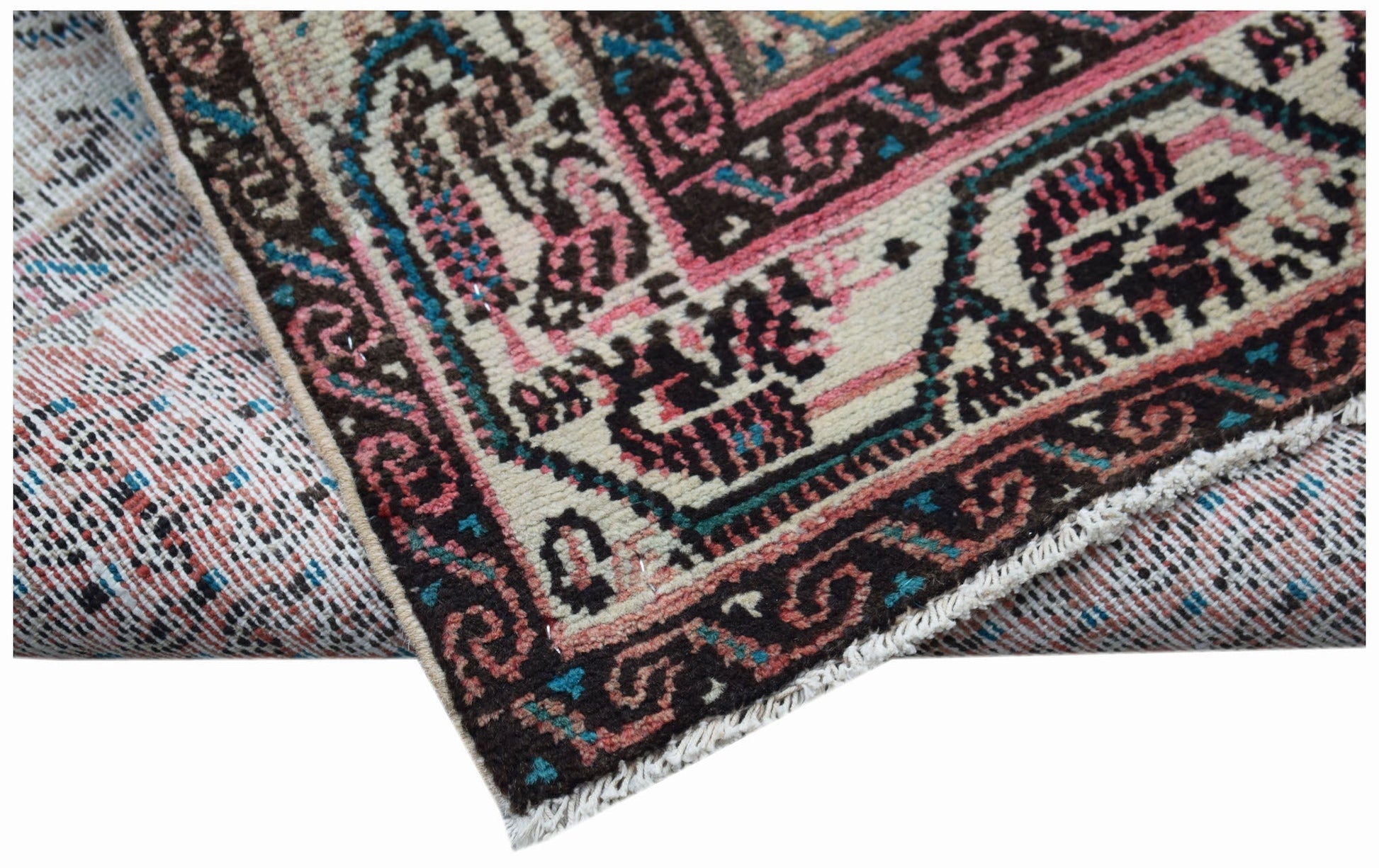 A handwoven vintage Persian rug featuring intricate geometric patterns in pink, blue, and brown.