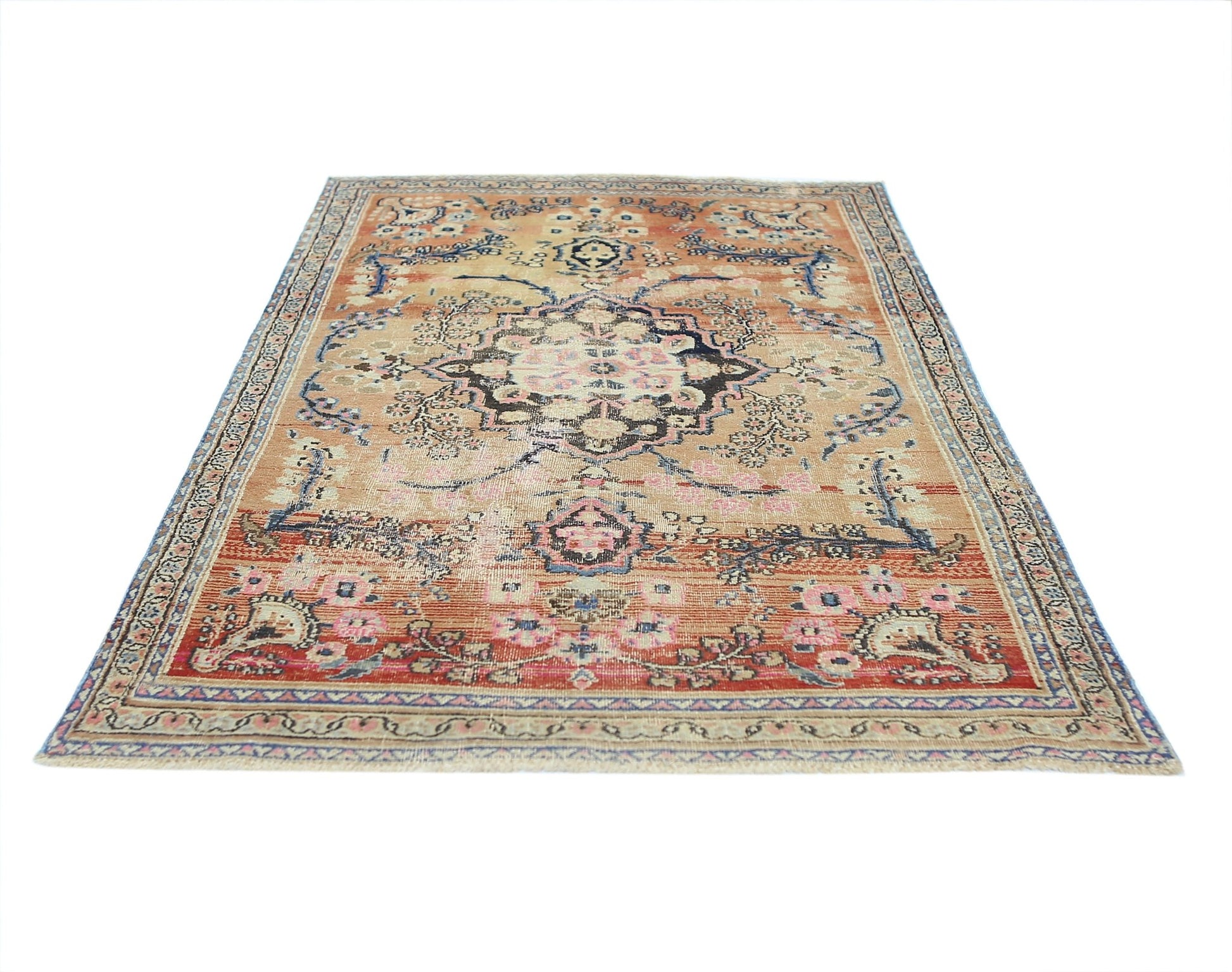 A vintage handmade Persian rug featuring a central floral medallion on a faded orange background.