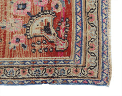 A vintage Persian rug featuring a red field with intricate floral patterns and a blue border.