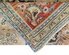 A folded vintage Persian rug featuring intricate floral patterns in red, blue, and beige tones.