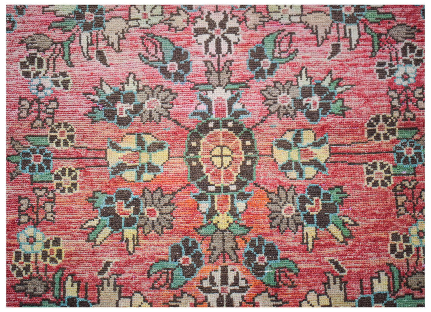 A vintage handwoven Persian rug featuring a floral medallion pattern in shades of red and green.