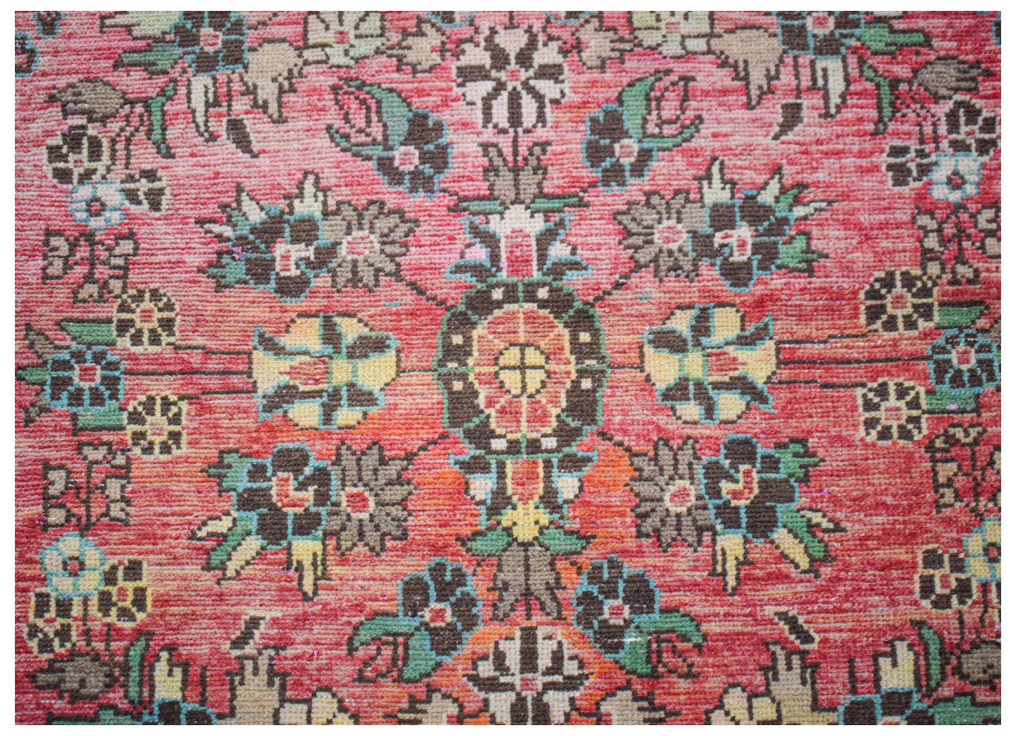 A vintage handwoven Persian rug featuring a floral medallion pattern in shades of red and green.