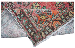 A handwoven vintage Persian rug featuring a floral pattern in red, orange, and brown tones.