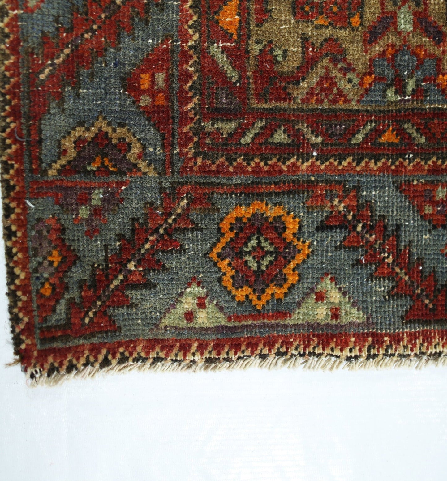 A close-up of a vintage Persian rug featuring intricate floral patterns in red, blue, and orange.
