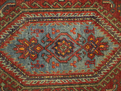 A vintage Persian rug featuring a central geometric medallion in blue, red, and orange tones.