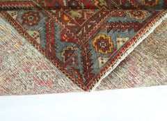 A folded vintage Persian rug featuring intricate geometric patterns in red, blue, and orange.