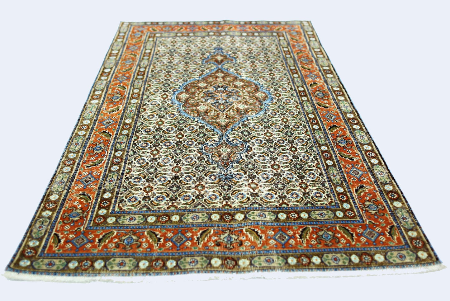 A vintage handmade Persian rug featuring a central medallion on a patterned cream field.