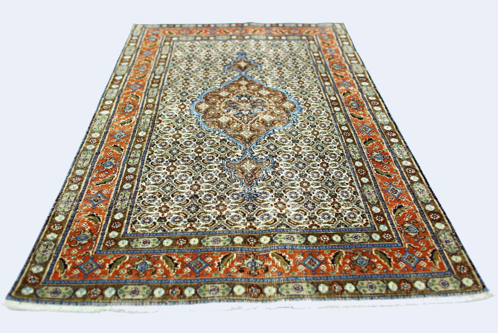 A vintage handmade Persian rug featuring a central medallion on a patterned cream field.