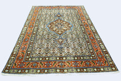 A vintage handmade Persian rug featuring a central medallion on a patterned cream field.