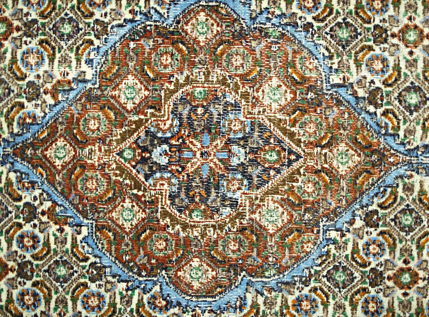 A vintage Persian rug featuring an intricate geometric medallion pattern in blue, red, and brown.