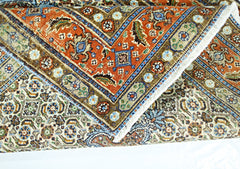 A folded vintage Persian rug featuring intricate floral patterns in orange, blue, and cream tones.