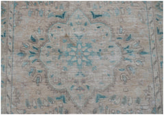 A vintage handwoven Persian rug featuring a faded floral medallion in blue and beige tones.
