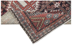 A handwoven vintage Persian rug featuring geometric patterns in red, black, and cream tones.