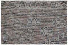 A close-up of a vintage handwoven Persian rug featuring a faded floral pattern and border.