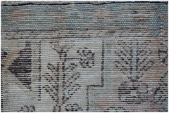 A close-up of a handwoven vintage Persian rug featuring intricate brown floral and geometric motifs.