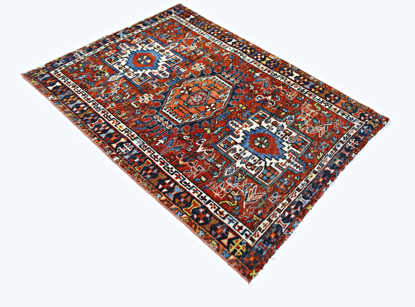 A rectangular vintage Persian rug featuring intricate geometric patterns in red, blue, and white.