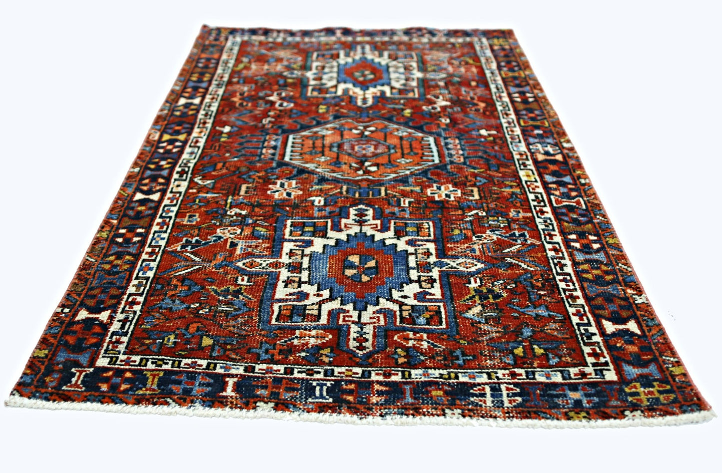 A rectangular vintage Persian rug featuring a geometric pattern in red, blue, and white.