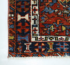A close-up of a vintage handmade Persian rug featuring intricate geometric patterns in red and blue.