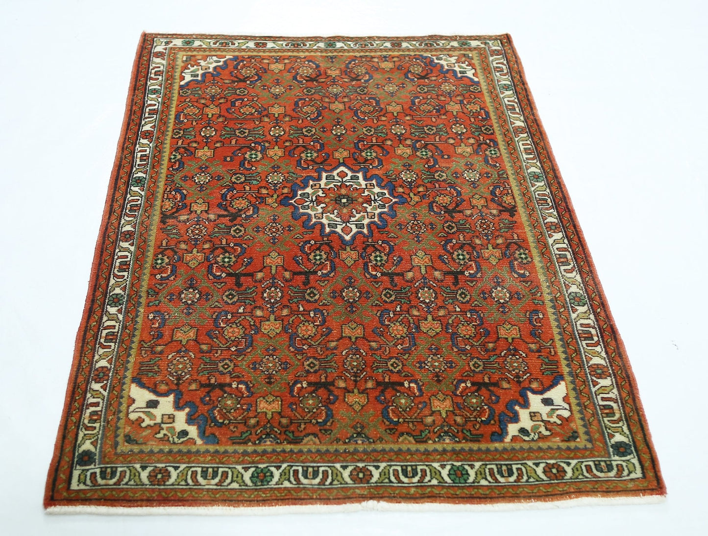 A rectangular vintage Persian rug featuring a detailed floral pattern in red, blue, and green.