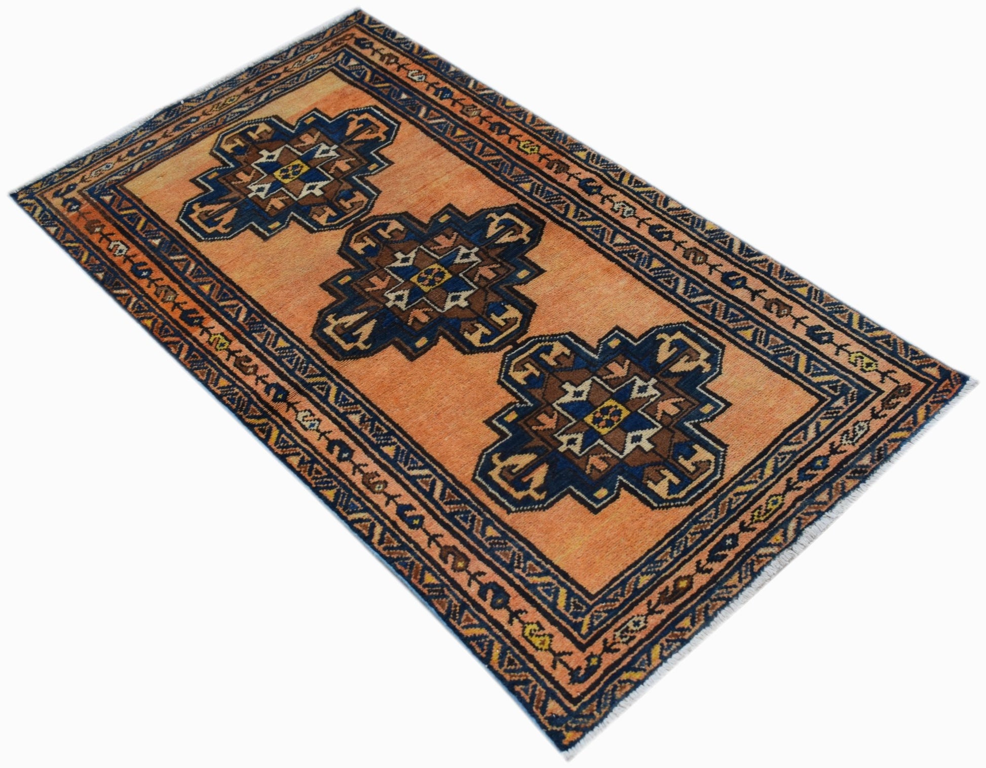 A vintage handwoven Persian rug featuring three dark blue geometric medallions on an orange field.