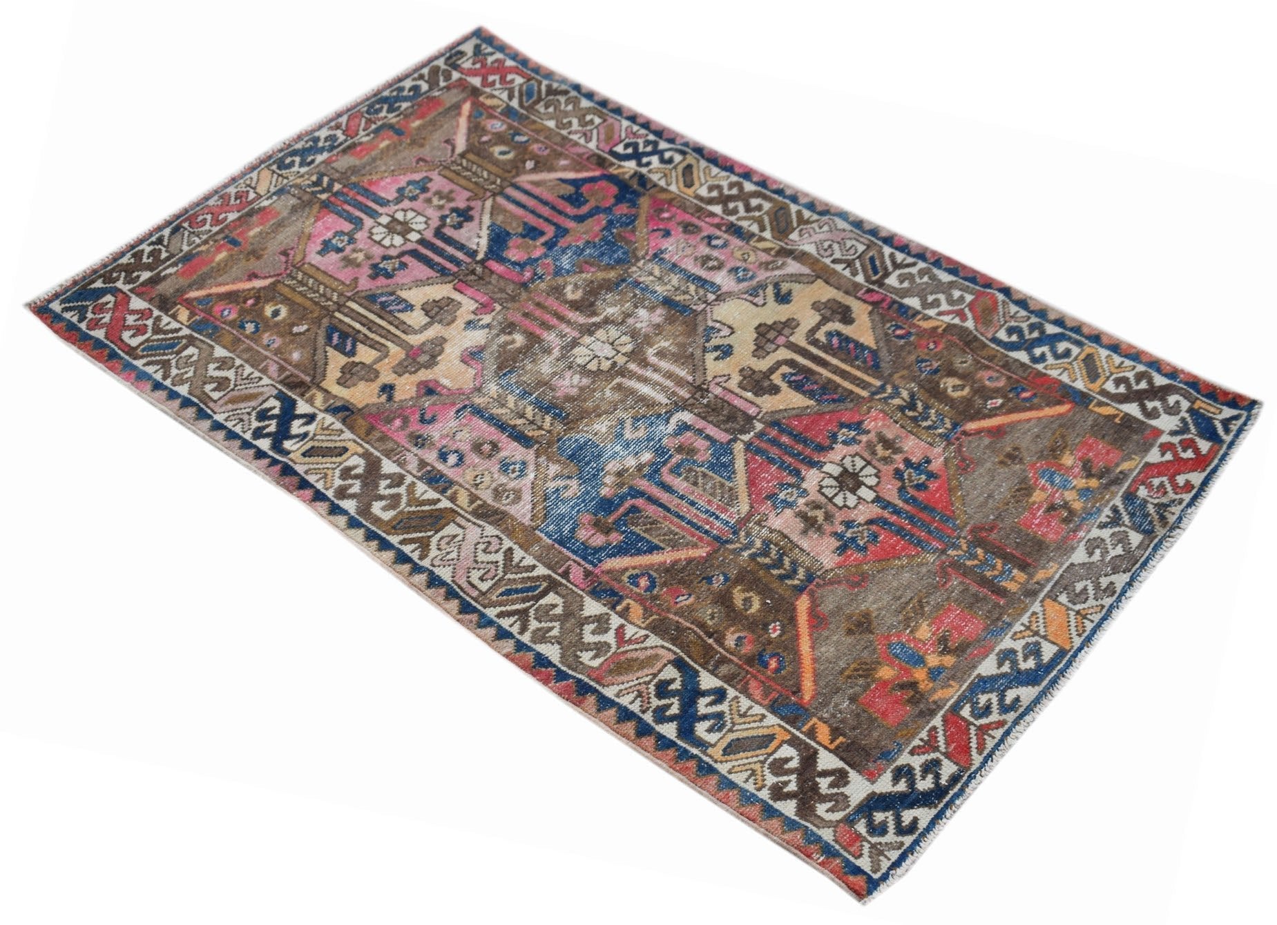 A vintage handwoven Persian rug featuring a distressed geometric pattern in blue, pink, and brown.