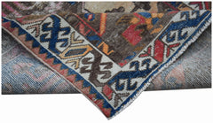 A folded vintage Persian rug featuring intricate geometric patterns in blue, red, and brown tones.