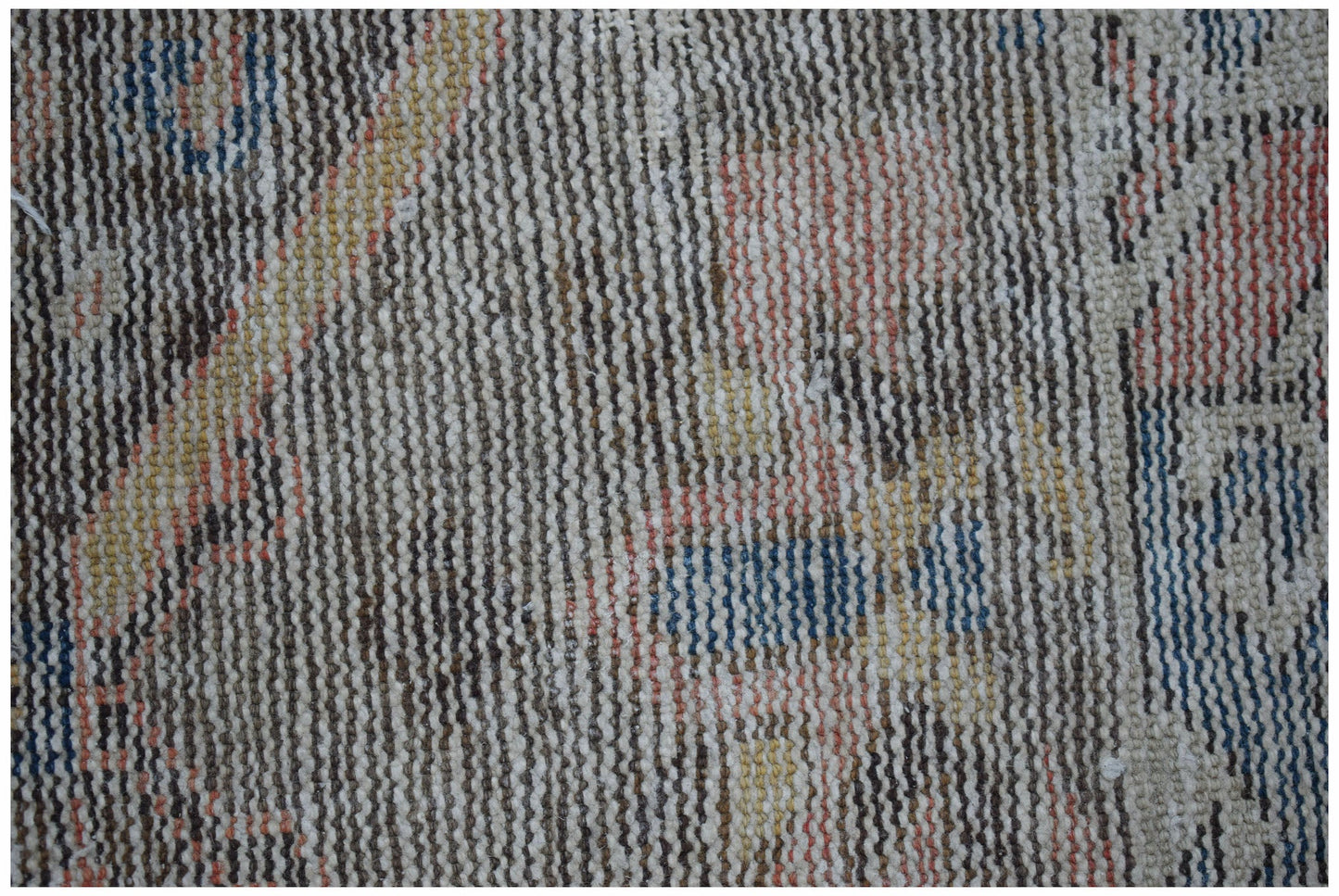 A close-up view of a handwoven vintage Persian rug featuring a worn, multi-colored wool pattern.