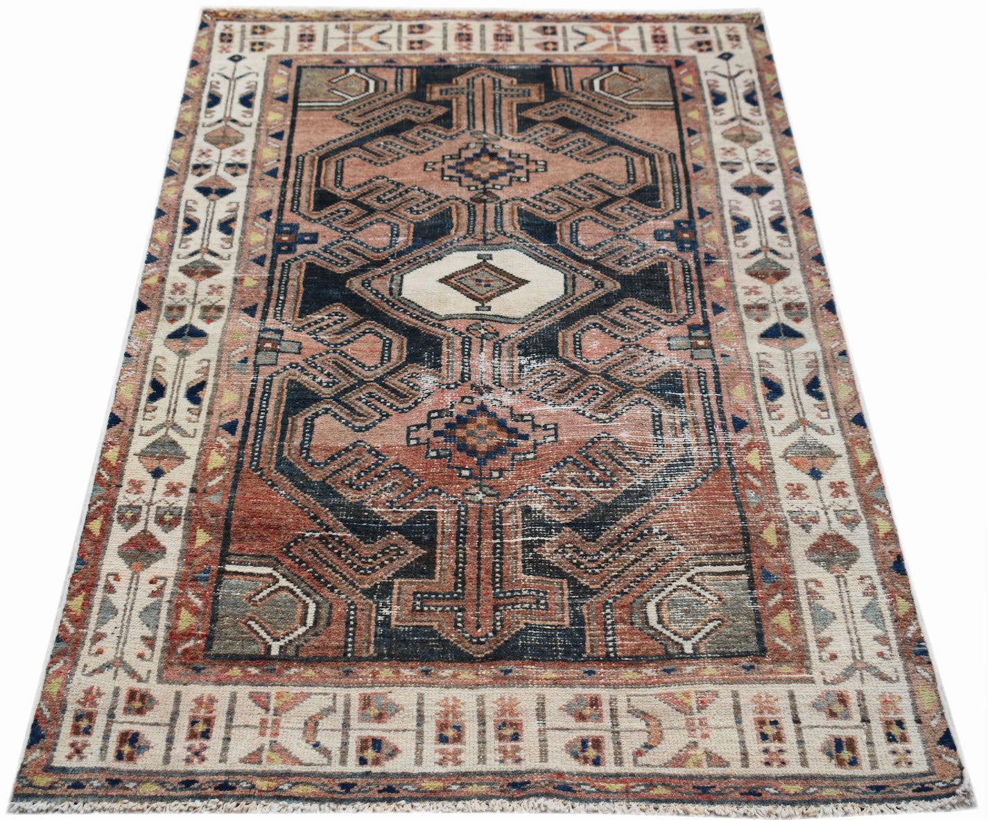 A vintage handwoven Persian rug featuring a geometric pattern in muted red, blue, and cream tones.