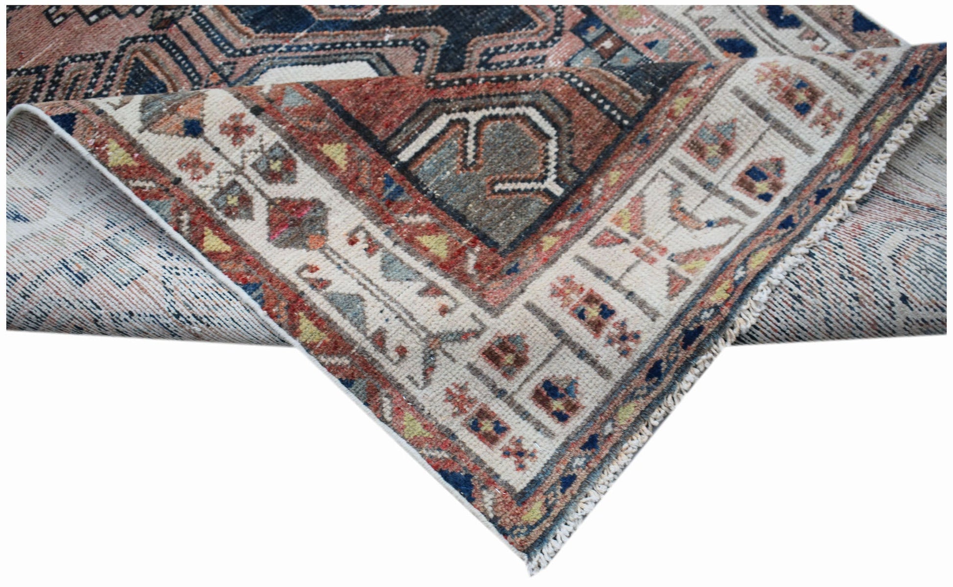 A handwoven vintage Persian rug featuring a geometric pattern in muted red, blue, and cream tones.