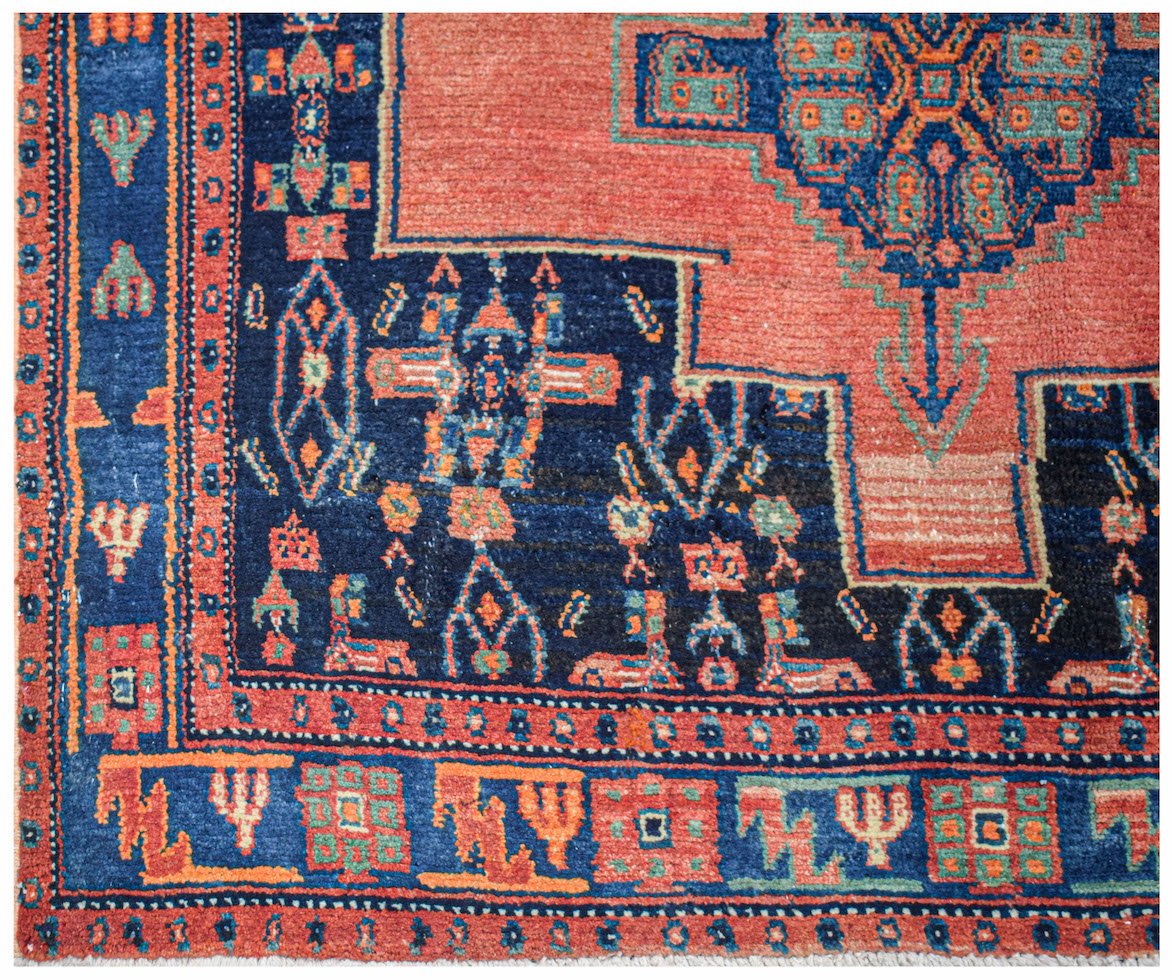 A handwoven vintage Persian rug featuring geometric patterns in red, blue, and green wool.