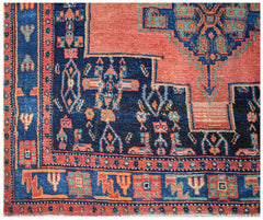 A handwoven vintage Persian rug featuring geometric patterns in red, blue, and green wool.