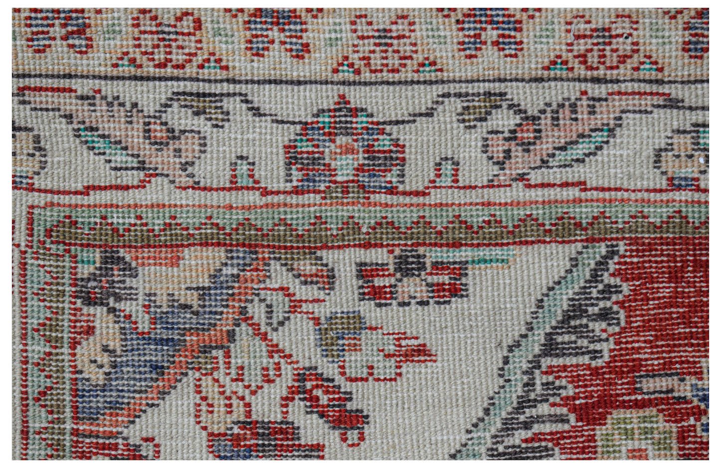 Close-up of a vintage Persian rug with intricate floral and geometric patterns in red, blue, and green.